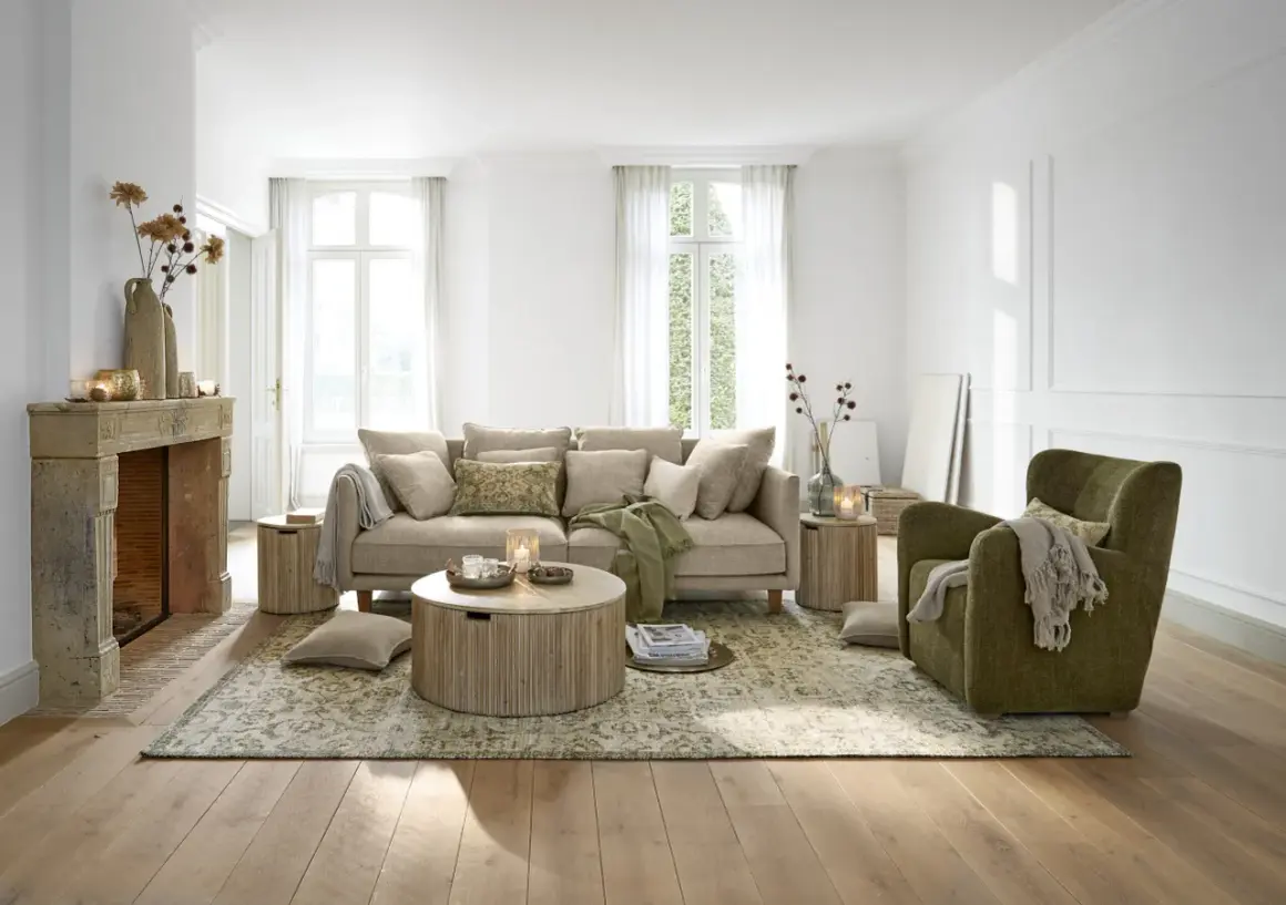 Gemütliches Wohnzimmer mit beigem Sofa, grünem Sessel und Kamin. Tolle Wohnzimmer Ideen für eine warme Atmosphäre.
